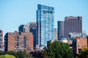 Modern skyscraper with glass facade, greenery and multiple buildings around it in Boston, USA